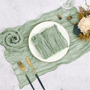 Sage green cheesecloth table runner with wrinkled texture and matching folded napkin