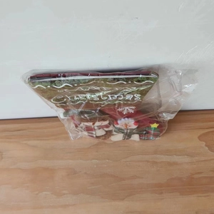Detail of red and green snowman Christmas stocking in transparent packaging on wood surface