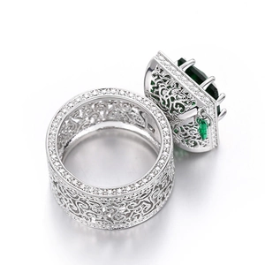 Macro shot of silver vintage ring featuring green emerald-cut stone and filigree detail
