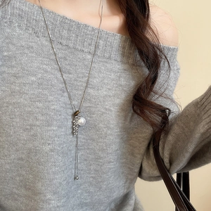 Detail of tiger eye and pearl Y-pendant on silver chain worn with a grey knit sweater