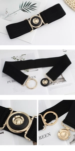 Detail of black elastic waist belt with gold leaf-shaped buckle and textured webbing