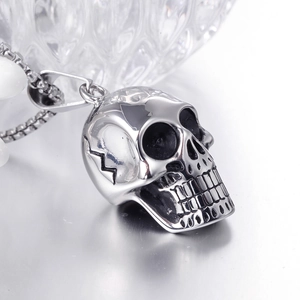 Macro shot of silver skull pendant in stainless steel on a matte metallic surface