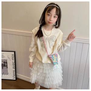 Détail du sweat-shirt beige fille avec nœud pailleté et jupe en tulle blanc