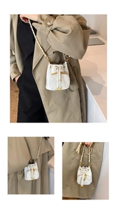 Mini white bucket bag with quilted pattern and chain strap shown on a model