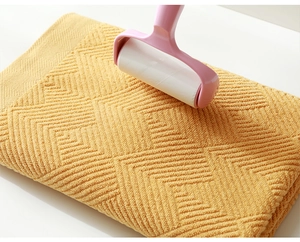 Close-up of pink lint roller removing dust on yellow geometric textured fabric