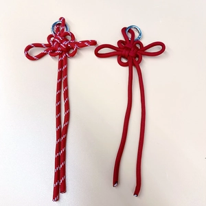 Handmade red Chinese knot charms with silver rings and long tassels on beige background