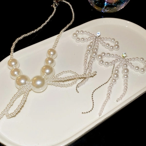 Detail of silver bow tassel and pearl necklace with matching earrings on tray