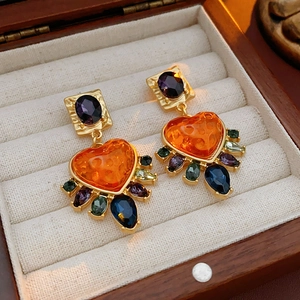 Detail of vintage heart earrings with colorful gemstones in a wooden jewelry box