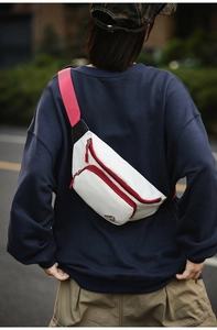 Weiße Sport-Brusttasche mit rotem Gurt am Rücken eines Models in der Stadt