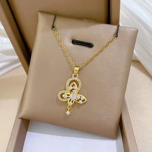 Close-up of golden butterfly necklace with stars and gems in a beige jewelry box