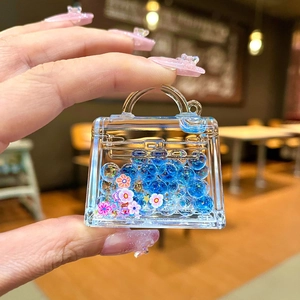 Detail of acrylic handbag keychain with blue liquid and floating sequins in hand
