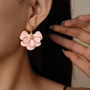 Close-up of pink enamel flower earrings with gold plating worn by a model