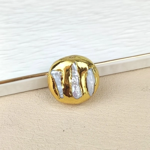 Detailed close-up of a gold-plated irregular freshwater pearl charm with metallic border