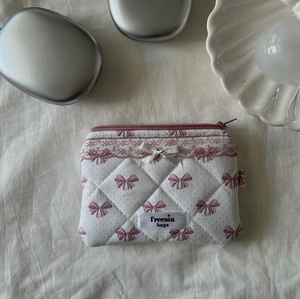 Detailed top view of quilted cotton cosmetic bag with pink bow pattern on beige fabric