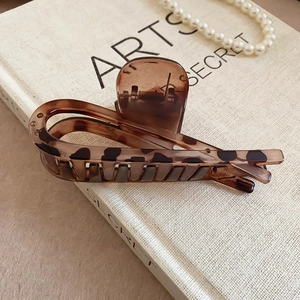 Detail of tortoiseshell leopard print hair claw clip on a vintage book with pearls