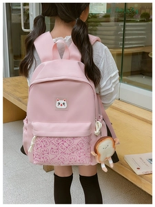 Pink kids backpack with cat face pattern and plush toast charm worn by a young girl