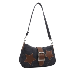 Detail of blue denim shoulder bag featuring star patches and metal buckle strap