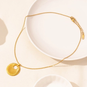 Macro view of golden stainless steel sunburst pendant with lobster clasp on porcelain