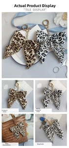 Detail of leopard print fabric bow charms in yellow and white with gold keychains