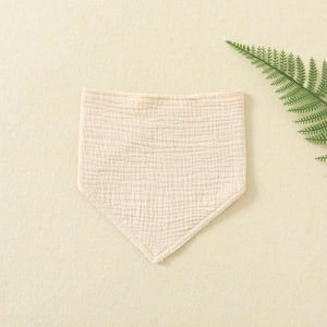 Detailed macro view of soft beige cotton gauze baby bandana bib with crinkled texture