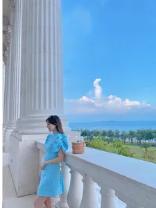 Detail of sky blue satin puff sleeve dress worn in an elegant outdoor coastal setting