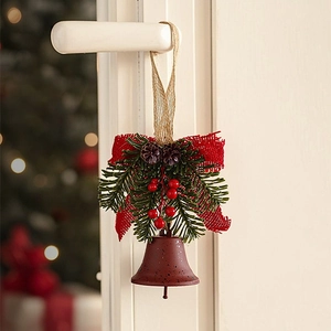 Rustic Christmas bell ornament with red burlap bow, pine needles and berries hanging on a door