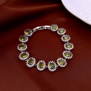 Détail du bracelet argenté avec pierres vert olive et zircons sur fond velours