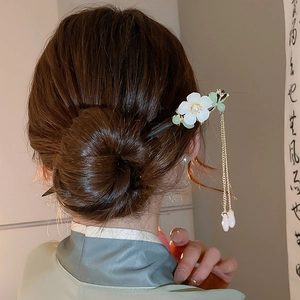 Detail view of flower hair stick with pearl tassels on braided hair for women
