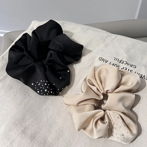 Detail of satin hair scrunchies set with sparkling rhinestones in black and beige