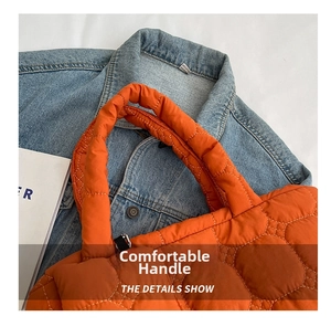 Detail of orange quilted tote bag with padded handles on a blue denim background