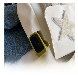 Detail shot of the side pocket on a white tote bag holding sunglasses with star patch