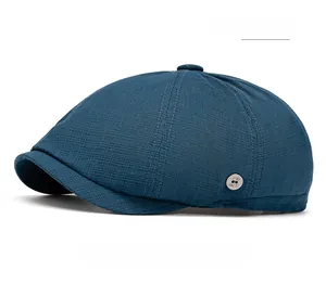Detail of dark blue newsboy cap with woven texture and a silver metal logo plaque