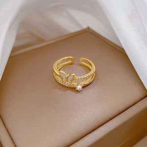 Détail macro de la bague papillon dorée avec perle blanche sur présentoir de luxe