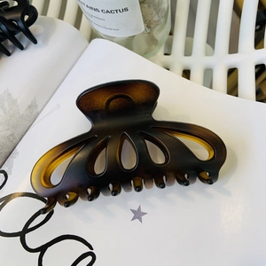 Detail of large dark brown tortoiseshell hair claw clip with hollow petal design