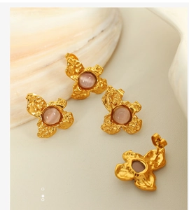 Detailed macro view of gold irregular lava texture earrings with pink bead inlay and shell
