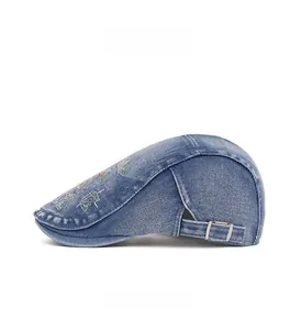 Side view of washed blue denim beret cap with colorful embroidery and metal buckle