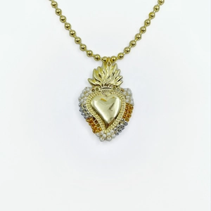 Macro shot of sacred heart pendant with intricate beadwork on golden necklace