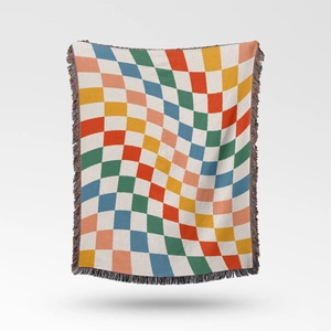 Detail of bohemian knit blanket with colorful warped checkerboard pattern and fringe edge