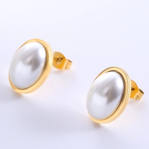 Macro view of gold stud earrings featuring oval faux pearl and polished metal edge