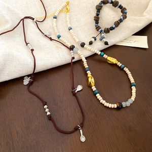 Detailed close-up of acrylic coffee bean beads and woven shell pendants on jewelry