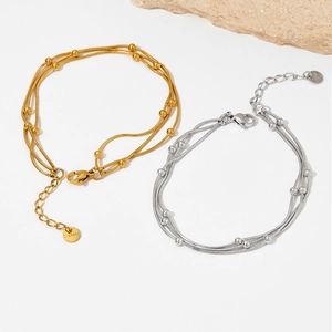 Détail de chaînes serpent multicouches dorées et argentées avec perles et tags s.steel