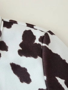 Close-up of cow print jacket showing brown and white pattern with shoulder stitching