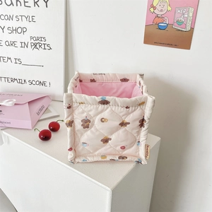 Detalle de la cesta de tela acolchada rosa con lindos estampados de perros de dibujos animados