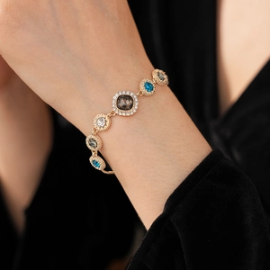 Detail of luxury gold bracelet with sparkling blue and clear crystals on a woman's wrist