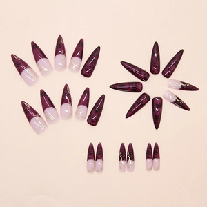 Macro detail of dark purple stiletto press on nails with gold swirls and black floral patterns