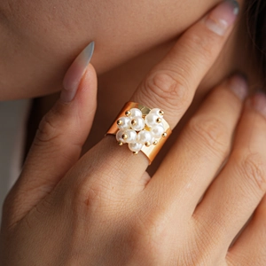 Detailed view of wide gold pearl flower ring on finger showcasing elegant vintage jewelry