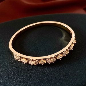 Détail du bracelet rigide plaqué or 18K avec relief floral et petites pierres claires