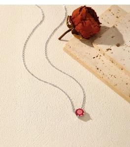 Close-up of S925 sterling silver necklace featuring a red garnet stone and a dried rose
