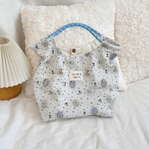 Detail of cartoon bear and bow patterns on striped canvas bag with blue braided handles