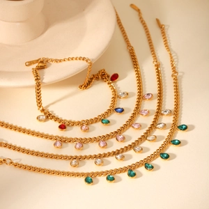 Detail of gold-plated stainless steel Cuban link bracelet with colorful teardrop zirconia